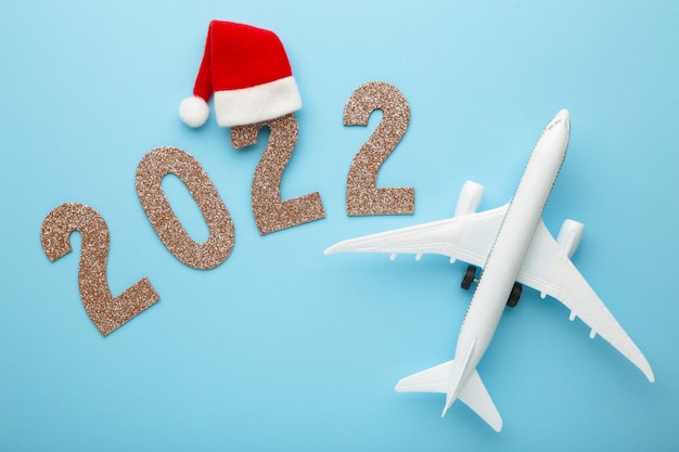 Weihnachtshintergrund mit Flugzeug und Aufschrift 2022 auf blauem Hintergrund. Weihnachtsfeiertage