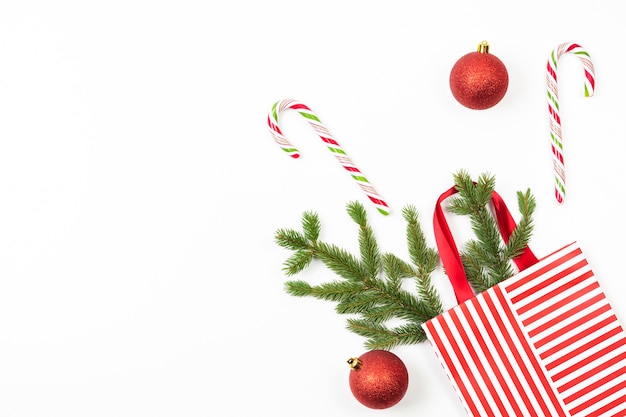 Weihnachtshintergrund mit Geschenkbeutel, Tannenzweig, Dekoration, Zuckerstangen auf Weiß