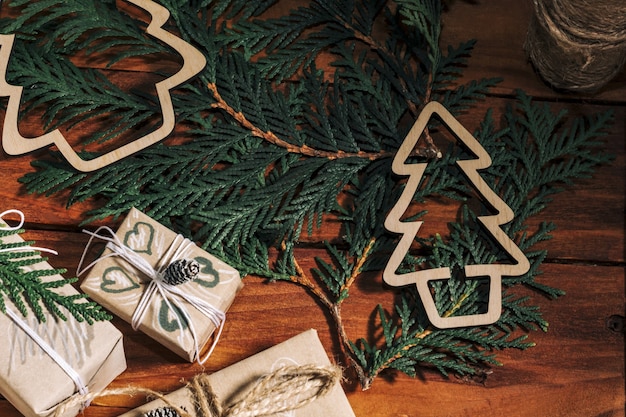 Weihnachtshintergrund mit handgemachten Geschenkboxen, Seilknäuel und Dekorationen mit Tannenzapfen und Twigson auf Holzhintergrund. Vorbereitung auf den Urlaub. Handgefertigt. Selektiver Fokus.