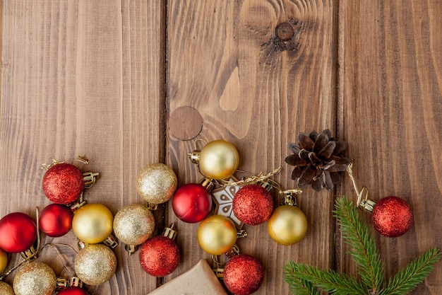 Weihnachtshintergrund mit Neujahrsspielzeug und Tannenzweig auf Holztisch.