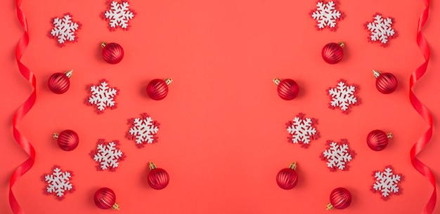 Weihnachtshintergrund mit Schneeflocken, roten Kugeln und Band