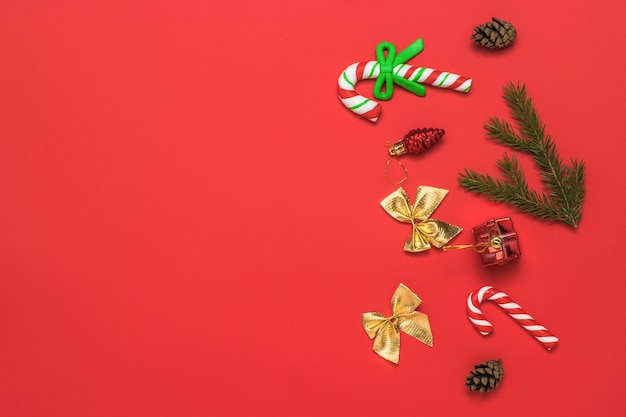 Weihnachtshintergrund mit Süßigkeiten, Fichtenzweigen und goldenen Schleifen.