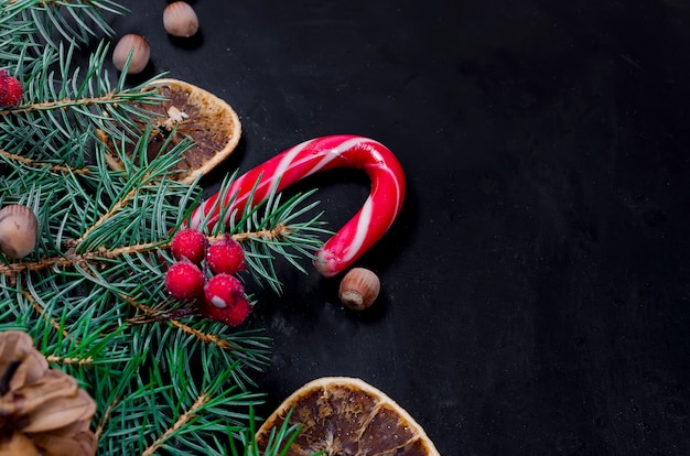 Weihnachtshintergrund mit Tanne, trockene kandierte Früchte, Süßigkeitsstöcke