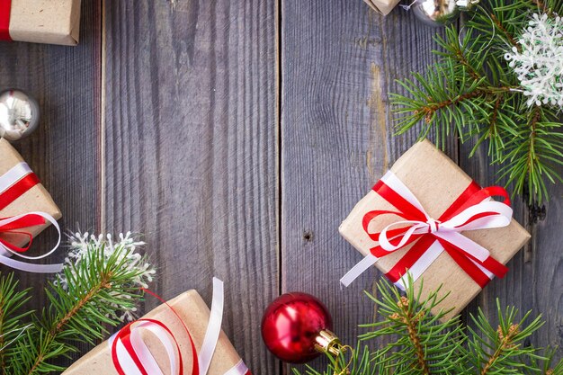 Weihnachtshintergrund mit Tannenbaum und Dekorationen und Geschenkboxen auf Holzbrett.