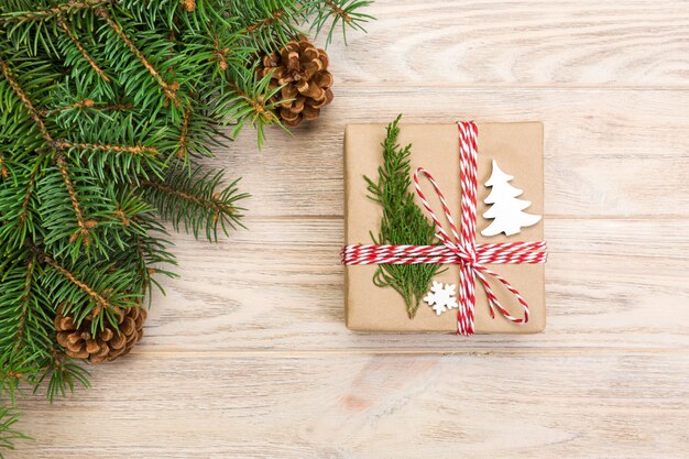 Weihnachtshintergrund mit Tannenbaum und Geschenkbox auf Holztisch. Draufsicht mit Exemplar