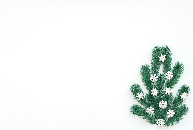 Weihnachtshintergrund mit Tannenbaum und kleinen weißen Schneeflocken.