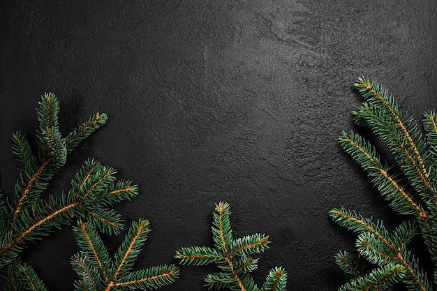 Weihnachtshintergrund mit Tannenbaumzweigen auf schwarzem Beton