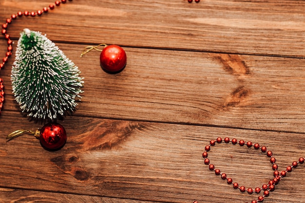 Weihnachtshintergrund mit Tannenzweig und rotem Spielzeug auf Holzbrettern.