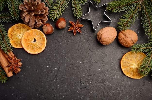 Weihnachtshintergrund mit Tannenzweigen, Kegeln, Nüssen und Scheiben der getrockneten Orange.