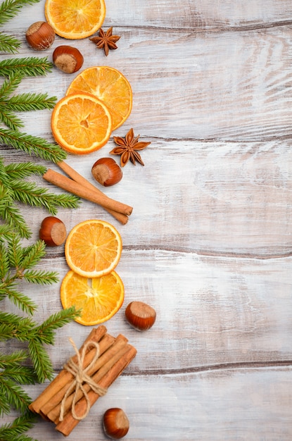 Weihnachtshintergrund mit Tannenzweigen, Nüssen, Gewürzen und getrockneten Orangen.