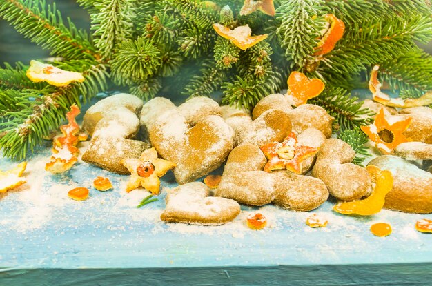 Weihnachtshintergrund mit Tannenzweigplätzchen, die mit Puderzucker auf Holzbrett bestreut sind