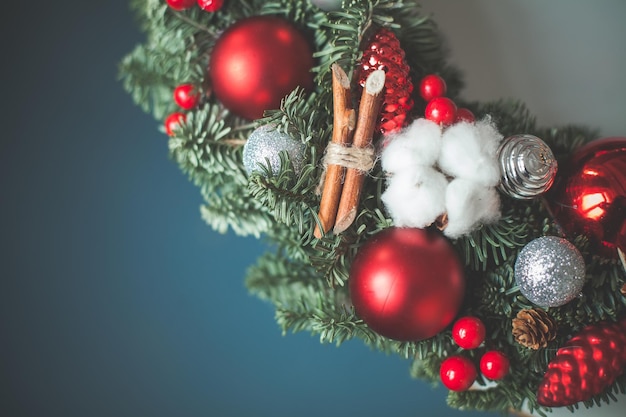 Weihnachtshintergrund mit Weihnachtsbaum-Zweig, Glaskugeln und Silvester-Stechpalmenbeeren auf Blau