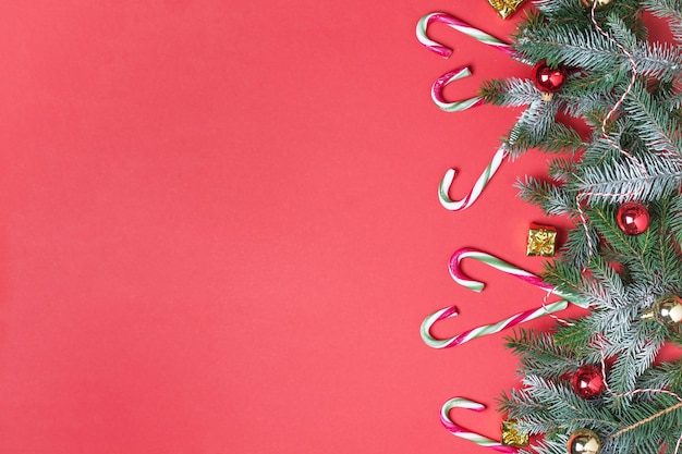 Weihnachtshintergrund mit Zuckerstangen und Weihnachtsbaum auf roter Weihnachtsgrußkarte