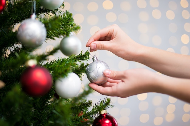 Weihnachtshintergrund - weibliche Hände, die Weihnachtsbaum schmücken