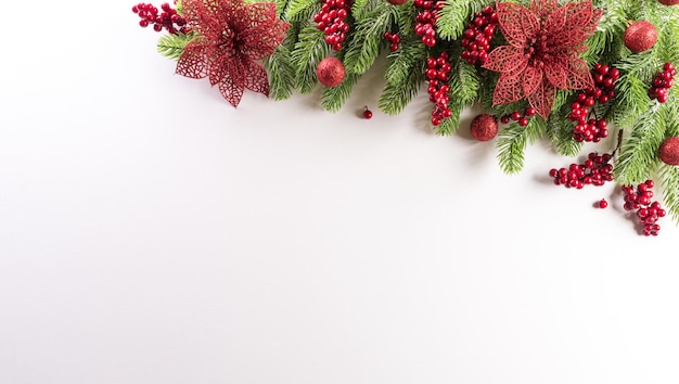 Weihnachtshintergrundkonzept. Draufsicht auf Fichtenzweige, Blumen und Beeren auf weißem Hintergrund.