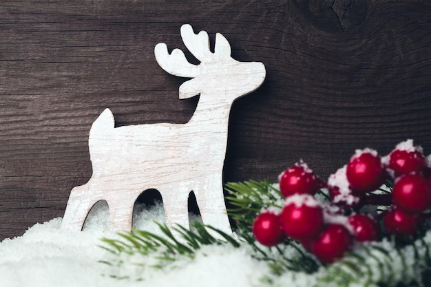 Weihnachtshirschspielzeug und Baum auf Schnee über hölzernem Hintergrund Weihnachtsvorbereitungskonzept