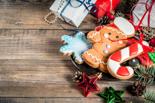 Weihnachtshölzerner Hintergrund mit Weihnachtslebkuchenplätzchen, Geschenken, Tannenbaumasten und Dekorationen. Kopieren Sie Platz