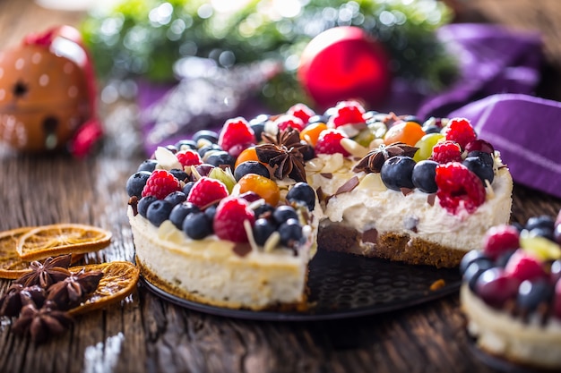 Weihnachtskäsekuchen mit frischen Fruchtbeeren Erdbeeren Himbeeren und Sternanis