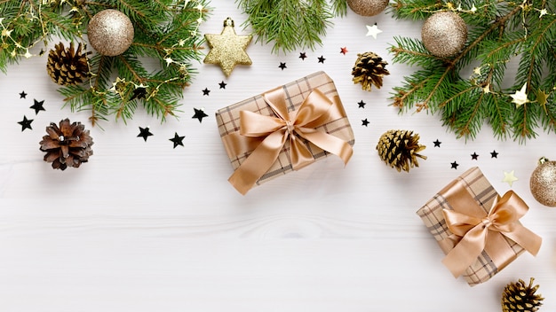 Weihnachtskarte mit Tannenzweigen, Geschenkboxen, goldenem Dekor und Holzornamenten, Konfetti mit Schnee. Weihnachtswohnung lag