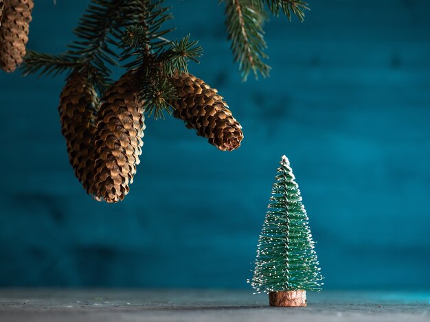 Weihnachtskarte mit Weihnachtsbaumzweigen und einem kleinen Weihnachtsbaum auf blauem Hintergrund aus Holz