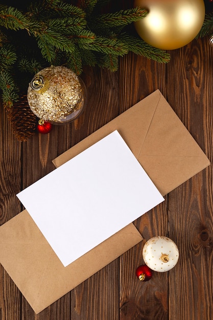 Weihnachtskartenmodell. Weiße minimale leere Postkarte auf Holztisch mit festlichen Dekorationen und Bastelbriefen.