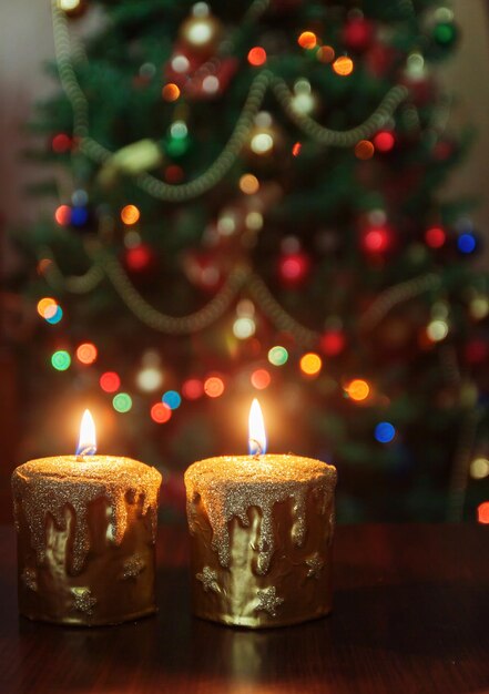 Weihnachtskerze vor einem Weihnachtsbaum mit funkelnden Lichtern und Kopienraum