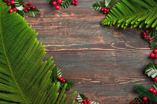 Weihnachtskiefernblatt und Mistel auf Holztisch, rot