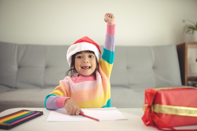 Weihnachtskind Brief an den Weihnachtsmann schreiben, Kind in Weihnachtsmütze schreiben Wunschliste
