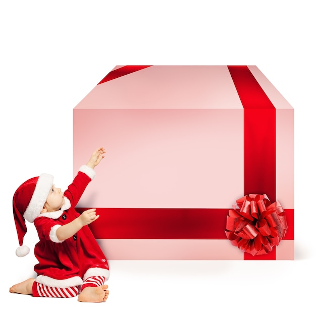 Weihnachtskind in Santa Hat und Big Gift Box. Weihnachtskonzept auf weißem Hintergrund