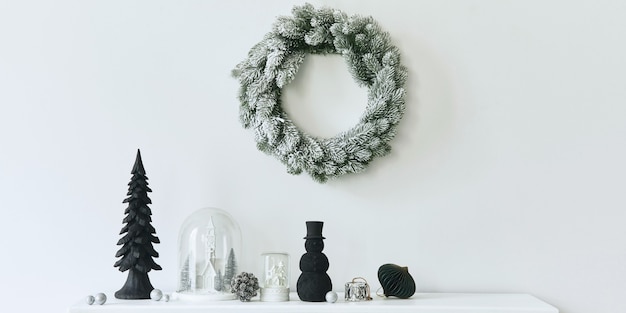 Weihnachtskomposition auf dem weißen Kamin im Wohnzimmer mit schöner Dekoration. Weihnachtsbaum und Kranz, Kerzen, Sterne, Licht. Platz kopieren. Vorlage.