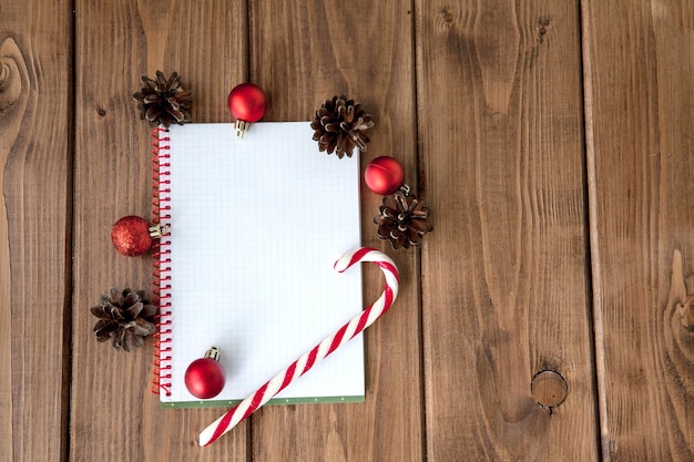 Weihnachtskomposition auf einem Holztisch mit Notizbuch mit Plänen für das Jahr.