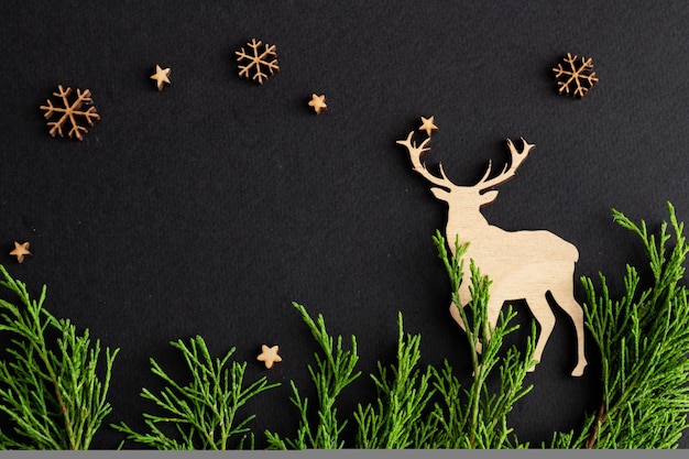 Weihnachtskomposition auf schwarzem Hintergrund aus Holz Hirsch- und Tannenkopierraum