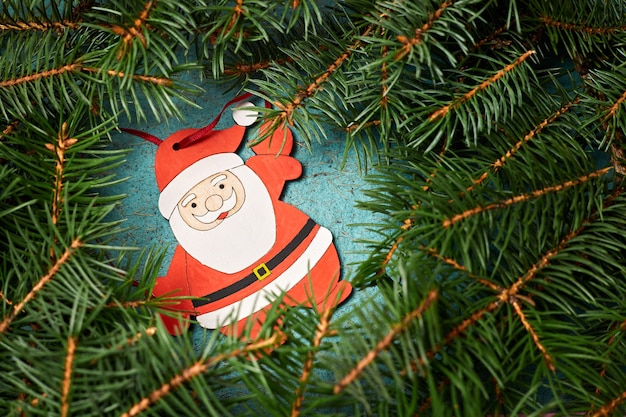 Weihnachtskomposition aus Holzfigur des Weihnachtsmannes, umgeben von Tannenzweigen
