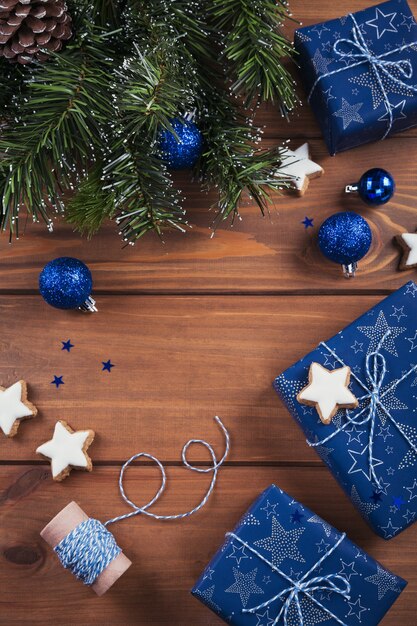 Weihnachtskomposition. Geschenke, Tannenzweige, blaue Verzierungen auf Holz. Weihnachts-, Winter-, Neujahrsfeiertagskonzept. Flache Lage, Draufsicht, Kopierraum