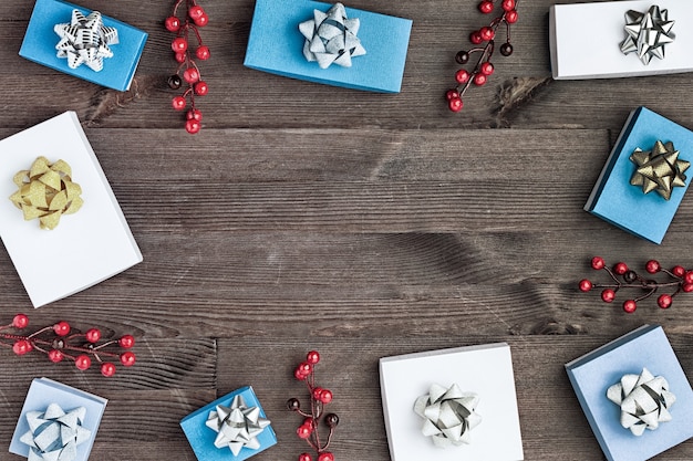 Foto weihnachtskomposition, in einem kreis sind geschenkboxen mit goldenen und silbernen schleifen und zweigen mit roten beeren.