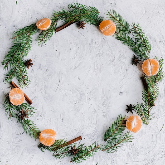 Weihnachtskomposition mit Baumzweigen, Mandarinen, Zimt und Anis in Form eines Kreises