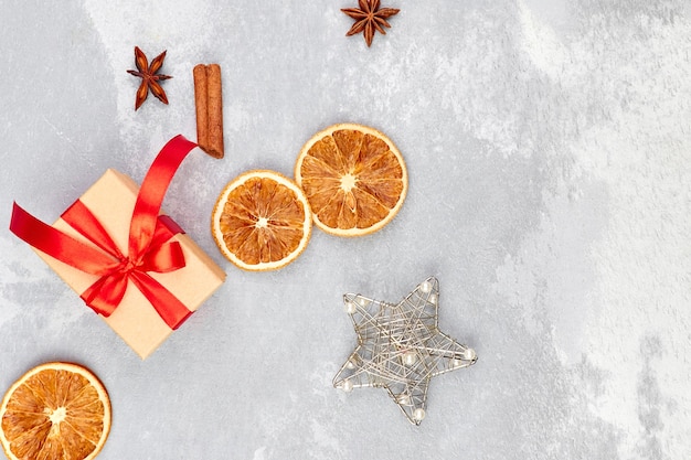 Weihnachtskomposition mit Geschenkbox, trockenen Orangen und Gewürzen