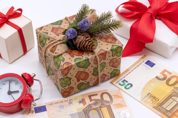 Weihnachtskomposition mit Geschenkboxen 50 Euro und einem Wecker Flat Lay