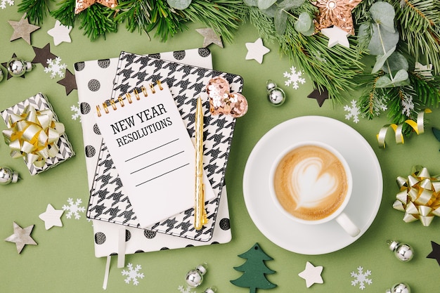 Weihnachtskomposition mit Kaffee, Notizbuch und Dekorationen in grünen und schwarzen Farben. Flache Lage, Ansicht von oben