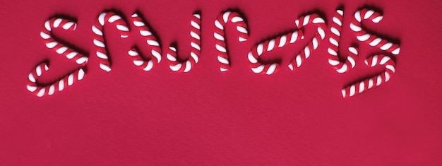 Weihnachtskomposition mit Rahmen aus Zuckerstangen auf rotem Hintergrund Platz für Textbanner kopieren