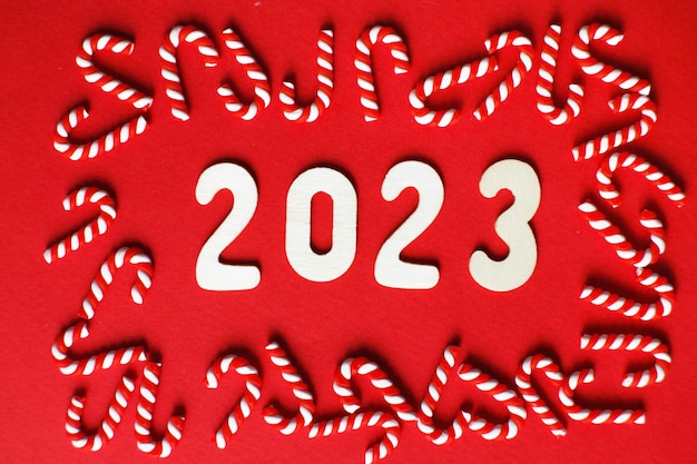 Weihnachtskomposition mit Zuckerstangen und Nummer 2023 auf rotem Hintergrund Platz für Text kopieren