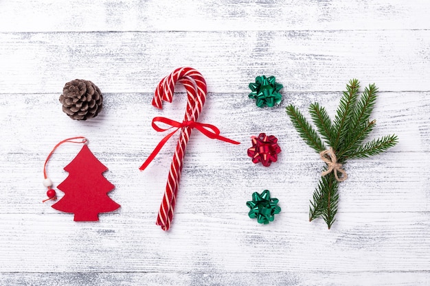 Foto weihnachtskomposition. rote geschenke, tannenbaum, tannenzweig und kegel, zuckerstangen auf holzhintergrund. flache lage, ansicht von oben - image