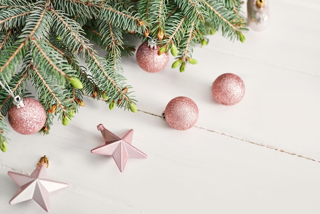 Weihnachtskomposition. Tannenzweige auf weißer Holzwand Flache Lage, Draufsicht, Kopierraum. Weihnachten Stillleben. Weihnachtsrahmen aus Tannenzweigen und rosa Spielzeug. Frohes neues Jahr