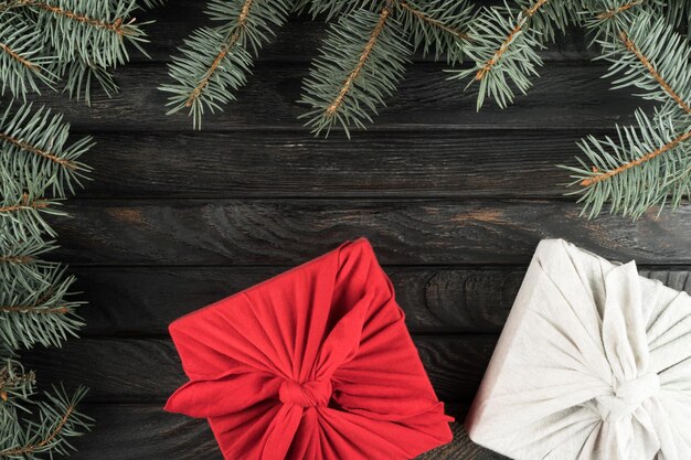 Weihnachtskomposition umweltfreundliche wiederverwendbare rot-weiße Furoshiki-Verpackung von Geschenkboxen mit dekoriertem Fichtenzweig