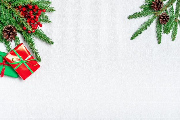 Weihnachtskomposition. Weihnachtsgeschenk, Tannenzapfen, Tannenzweige auf weißem Wellpappenhintergrund. Flache Lage, Draufsicht, Kopierraum.