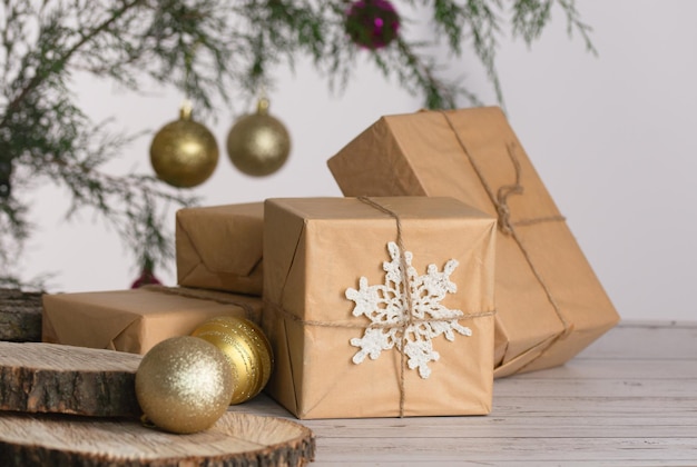 Weihnachtskompositionsgeschenke in handwerklicher Verpackung, goldene Kugeln, Tannenzweig, weißer Hintergrund