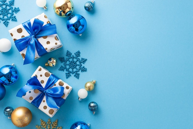 Weihnachtskonzept Draufsichtfoto von weiß-blauen und goldenen Kugeln, stilvollen Geschenkboxen mit Schleifen und Schneeflockenornamenten auf isoliertem pastellblauem Hintergrund mit leerem Raum