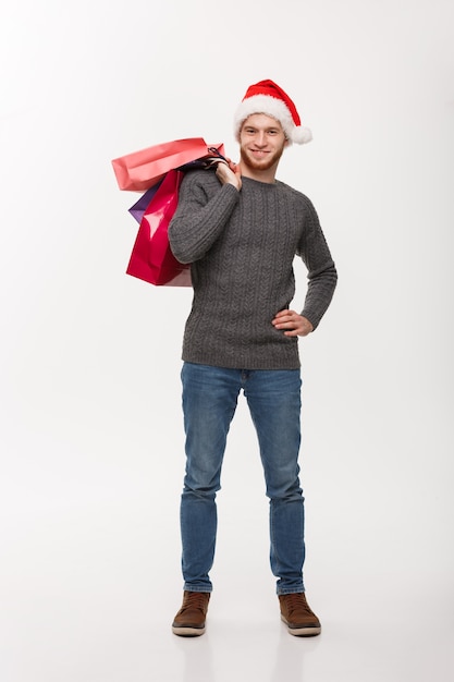 Weihnachtskonzept - junger hübscher Bartmann glücklich mit Einkaufstasche in der Hand lokalisiert