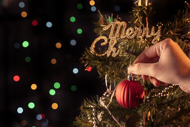 Weihnachtskonzept - schöne Dekorkugel, die am Weihnachtsbaum mit funkelndem Lichtfleck hängt