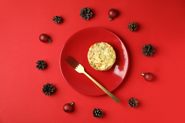 Weihnachtskonzept von leckerem Essen mit Olivier-Salat auf rotem Hintergrund